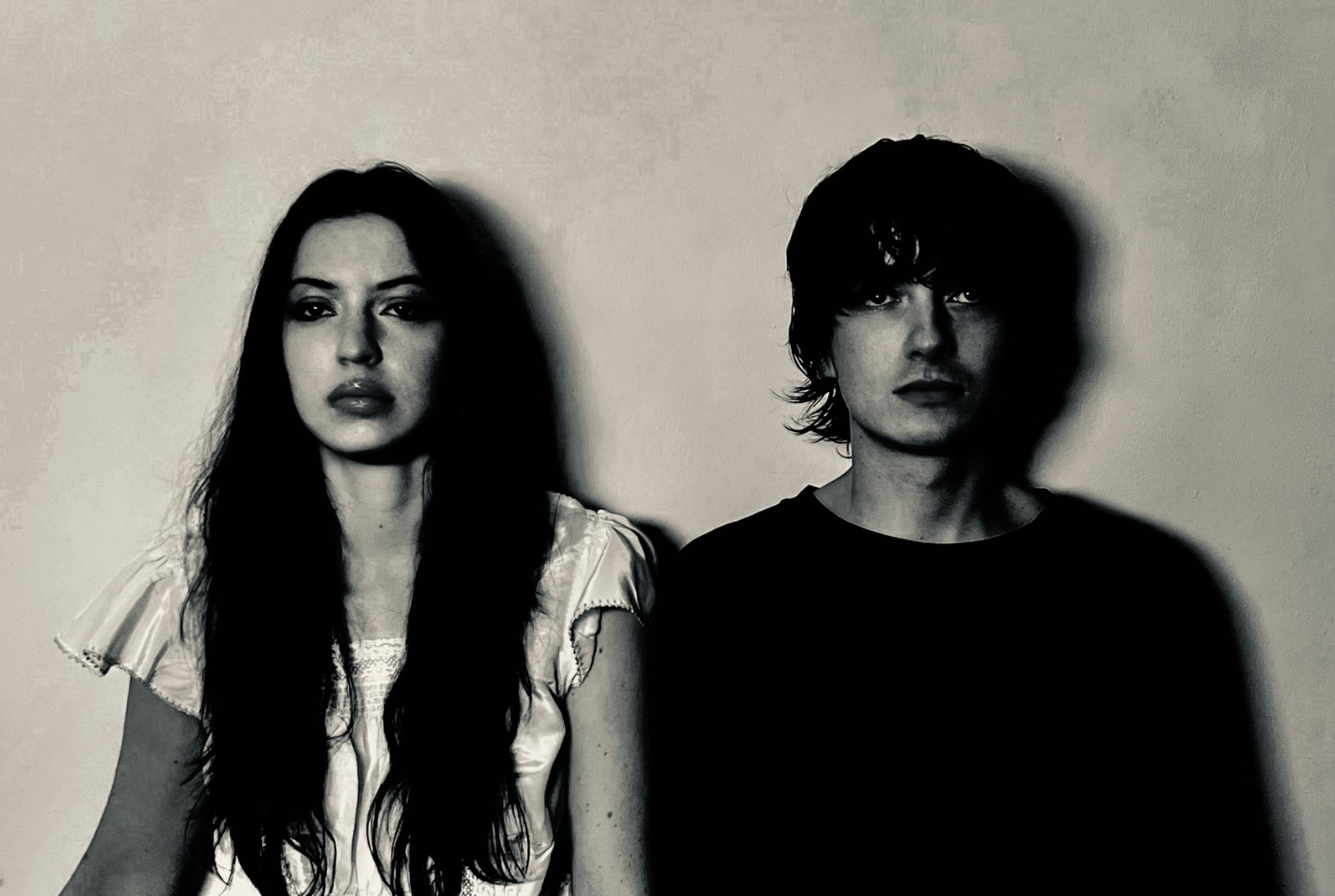 Members of the band Witch Post leaning against a wall in black and white.